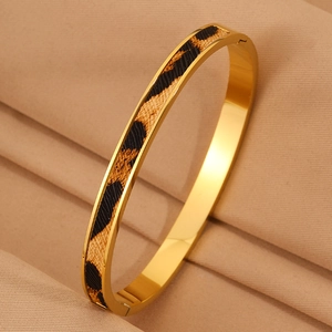 Dettaglio di un bracciale in acciaio dorato con inserto leopardato e finitura lucida