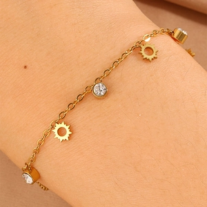 Detail of gold titanium steel bracelet featuring sun charms and zircon stone pendants