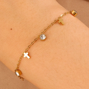 Close-up of gold-plated bracelet with shimmering cross charms and sparkling crystal stones