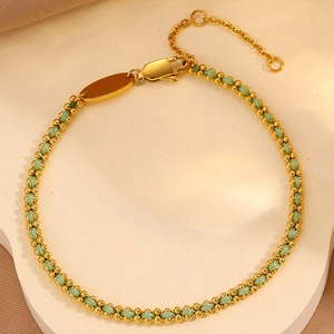 Detailed macro view of woven green rope bracelet with gold beads and lobster clasp closure