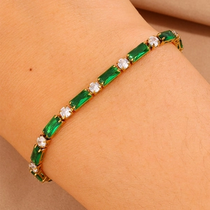 Dettaglio del bracciale in titanio dorato con zirconi verdi taglio smeraldo sul polso