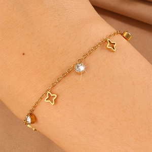 Close-up of gold stainless steel bracelet with clover charms and cubic zirconia on wrist