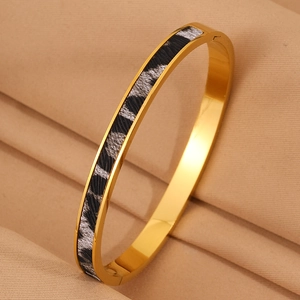 Dettaglio del bracciale in acciaio dorato con stampa leopardata e chiusura a cerniera