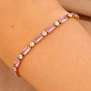 Dettaglio di un bracciale in acciaio al titanio dorato con zirconi rosa al polso