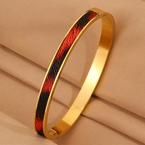 Dettaglio del bracciale in acciaio inossidabile dorato con intarsio rosso e nero