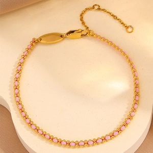 Detail of woven bracelet with gold metal beads, pink braided cord and lobster clasp