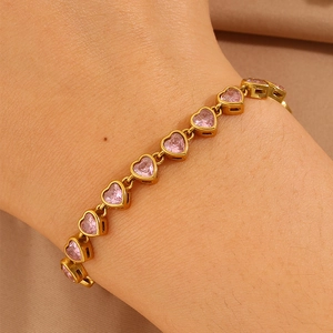 Detailed view of women's gold-plated tennis bracelet with pink heart-shaped crystals