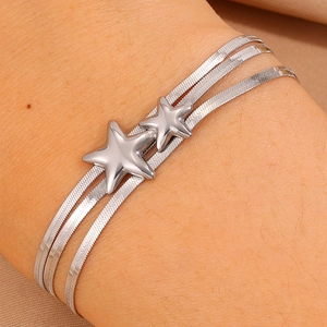 Gros plan d'un bracelet triple chaîne serpent en argent avec breloques étoiles polies
