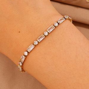 Dettaglio di un bracciale tennis dorato con zirconi rotondi e rettangolari alternati