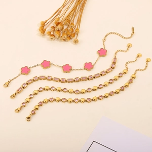 Detailed macro view of four gold-plated bracelets featuring pink clover and heart charms