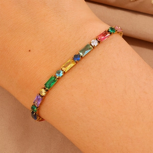 Dettaglio di un bracciale tennis con zirconi arcobaleno e finitura oro sul polso