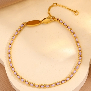 Detailed macro view of woven purple cord bracelet with polished gold metal beads and clasp