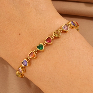 Close-up of a gold-plated bracelet with multicolored heart-shaped crystals on wrist