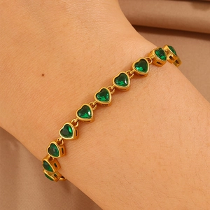 Detail of gold-plated heart bracelet featuring faceted green zircons on a wrist
