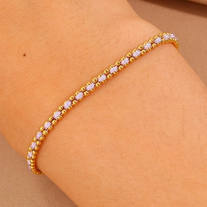 Macro shot of minimalist purple woven bracelet with gold beads worn on a wrist
