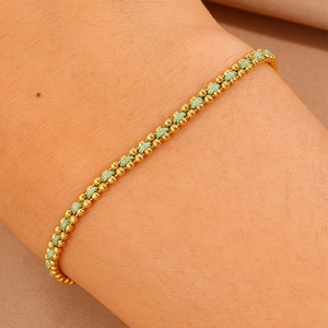 Close-up of light green braided rope bracelet with 18k gold beads on woman's wrist