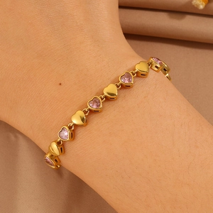 Close-up of 18k gold heart bracelet with pink gems on woman's wrist