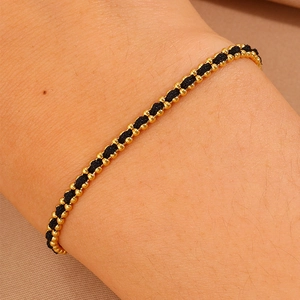 Macro detail of minimalist black woven cord bracelet with 18k gold-plated beads on wrist