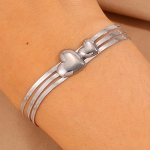 Gros plan sur un bracelet serpent multicouche argenté avec pendentifs en cœur