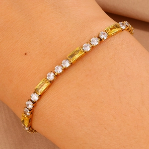 Dettaglio del bracciale in titanio dorato con pietre gialle rettangolari e zirconi bianchi