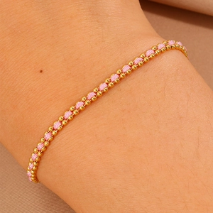 Detail of pink woven bracelet with double-row golden beads worn on a wrist