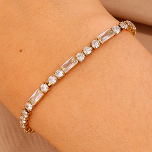 Dettaglio del bracciale in acciaio dorato con zirconi quadrati e rotondi alternati su polso