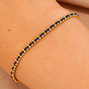 Detail view of handmade red braided cord bracelet with polished gold-toned metal beads