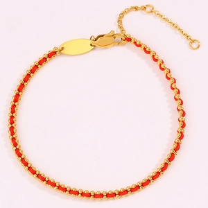 Detailed macro view of woven red string bracelet with gold beads and lobster clasp