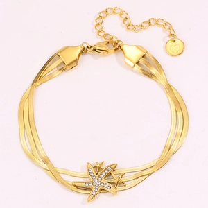 Détail d'un bracelet triple chaîne serpent dorée avec étoile de mer et pampille cœur