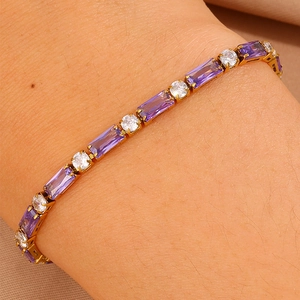 Dettaglio di bracciale tennis dorato con zirconi viola rettangolari e bianchi tondi