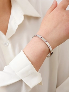 Dettaglio macro del bracciale argentato lucido con zirconi rosa incastonati con eleganza