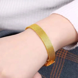 Gros plan d'un large bracelet en maille milanaise dorée avec une boucle carrée en métal