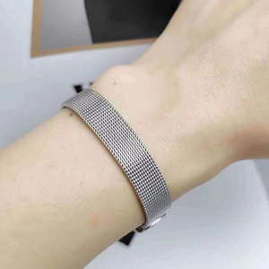 Détail d'un bracelet en acier à maille argentée avec fermoir pliant sur un poignet