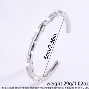Macro-opname van zilveren C-vormige manchetarmband met parels, strass en 6cm diameter detail