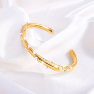 Detailopname van gouden titanium stalen armband met parels en kristallen op zijde