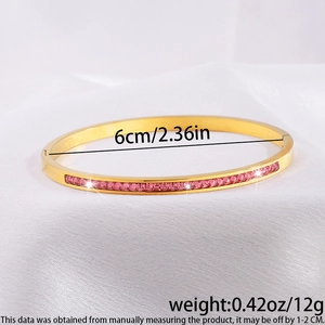 Vista detallada de un brazalete de acero dorado con piedras de circonita rosa engastadas