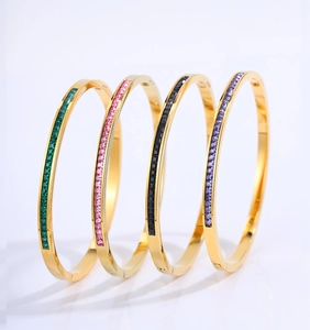 Detalle de cuatro brazaletes de acero dorado con incrustaciones de circonitas de colores