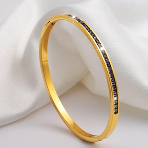 Vista detallada del brazalete de acero dorado con piedras púrpuras brillantes