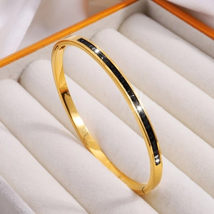Detalle de brazalete de acero al titanio dorado con cristales negros en caja de terciopelo