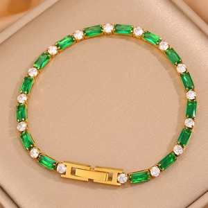 Détail du bracelet tennis doré avec pierres vert émeraude et zircons sur un support