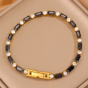 Détail du bracelet doré avec alternance de pierres noires rectangulaires et blanches rondes