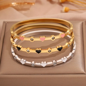 Dettaglio di tre bracciali a cuore in smalto con diamanti su portagioie in pelle