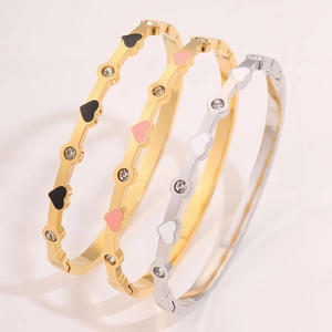 Dettaglio di bracciali rigidi a cuore in smalto oro e argento con piccoli cristalli