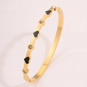 Dettaglio del bracciale in acciaio al titanio dorato con cuori smaltati neri e zirconi