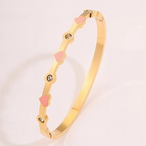 Dettaglio del bracciale in titanio dorato con cuori in smalto rosa e zirconi incastonati