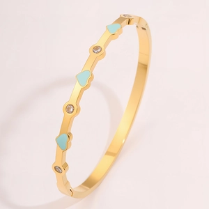 Dettaglio del bracciale in titanio dorato con cuori in smalto azzurro e zirconi incastonati