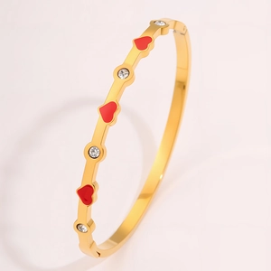 Vista dettagliata di un bracciale in titanio dorato con cuori rossi e cristalli
