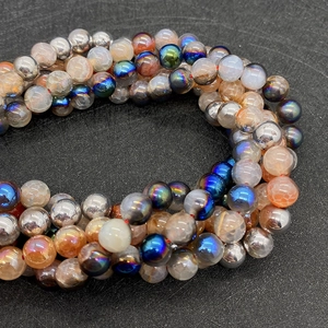 Macro detail of fire agate beads and metallic spheres on a red string for DIY jewelry