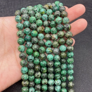 Macro view of natural African Turquoise round beads held in hand for size comparison