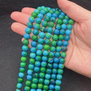 Close-up of green phoenix stone round beads held in hand for DIY jewelry making
